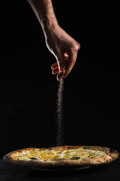food,circle,hand,pizza,black,person,cheese,dinner,studio,lunch,traditional,dark,fresh,spices,snack,meal,italian,italian food,delicious,cuisine
