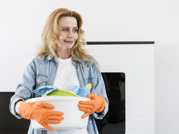 Woman holding basket with cleaning supplies Stock Photo by