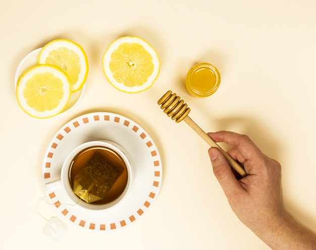 elevated,overhead,dipper,near,saucer,freshness,refreshment,teabag,refreshing,slice,porcelain,teacup,tasty,surface,high,citrus,one,ceramic,holding,beige,delicious,object,beverage,herbal,top,view,herb,bowl,jar,wooden,lemon,healthy,breakfast,cup,drink,honey,person,bag,backdrop,human,tea,health,fruit,tag,green,hand,wood,people,label,background