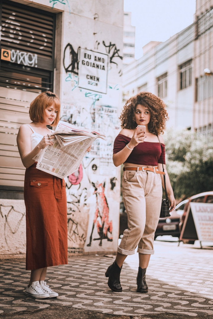 Free: Photo of One Woman Reading a Newspaper and Another Holding Her ...