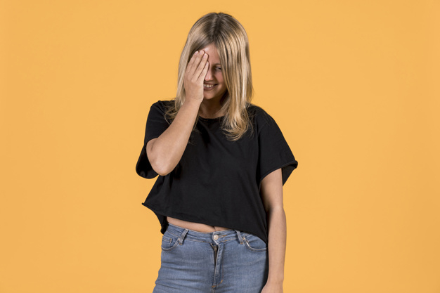 Free: Shy young woman standing against bright colored background