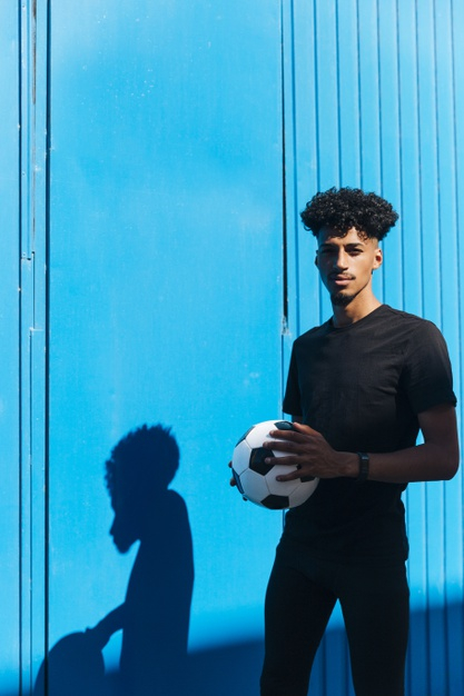 looking at camera,copy space,black hair,sporty,thin,african american,leisure,outdoors,looking,copy,pretty,active,curly hair,slim,curly,player,male,american,fit,teen,sunshine,young,african,shadow,stand,teenager,ball,healthy,person,game,smile,black,space,soccer,football,hair,blue,camera,blue background,background