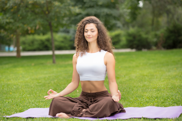 Free Photo  Fitness woman doing yoga exercises among green nature