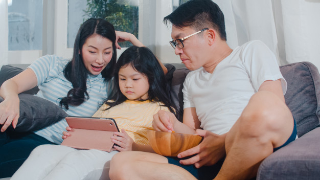 Happy young Chinese family using digital gadgets at home Stock