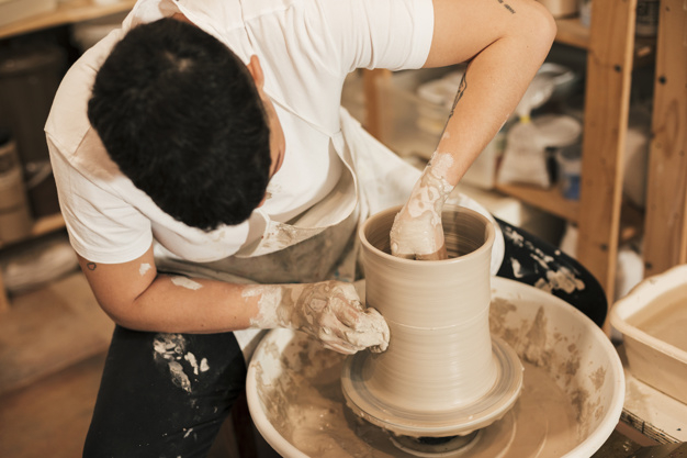 Free: Female potter clinging the pot on pottery wheel in the workshop Free  Photo 