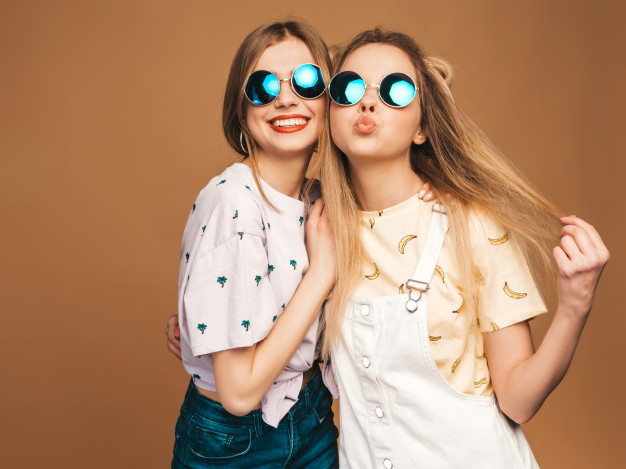 Two young beautiful smiling hipster girls in trendy summer clothes.Sexy  carefree women posing on the street background in sunglasses. Positive  models having fun and hugging.They going crazy Stock Photo