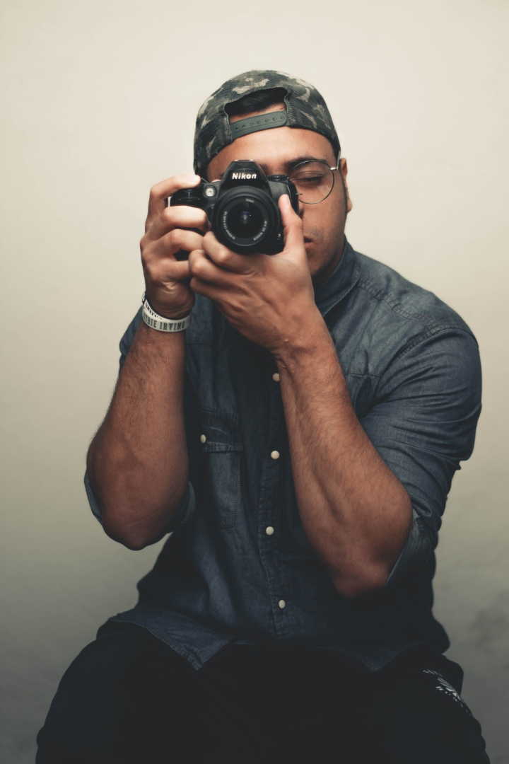 Portrait of asian man in white shirt holding digital camera with smile.  Handsome male photographer standing isolated on plain background copy  space. Photography business concept. Stock Photo | Adobe Stock