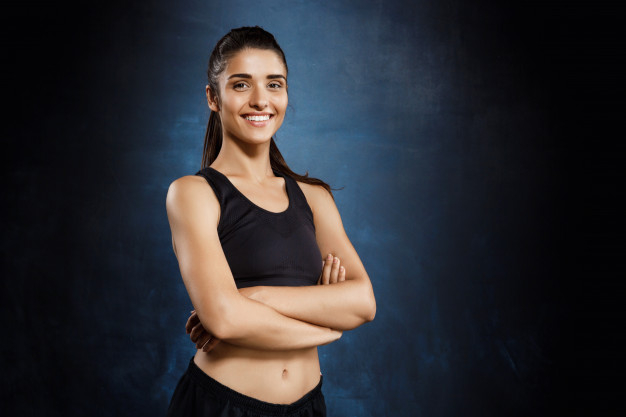 Free: Beautiful sportive girl posing with crossed arms over dark wall. Free  Photo 