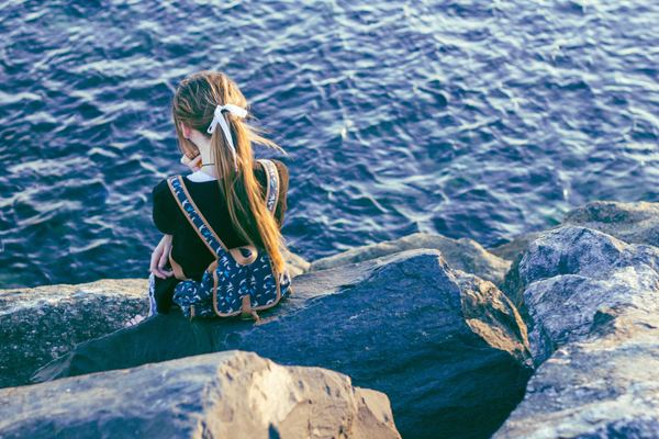 person,couple,man,college,woman,man,woman,hand,leg,rock,water,female,woman,outdoor,long hair,lakeside,backpack,nature,sat,sitting,solitude