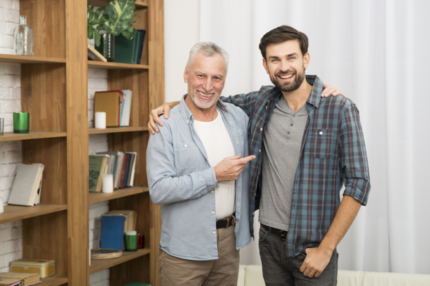 book,camera,man,happy,room,white,curtain,finger,father,relax,cloth,care,together,young,bookshelf,elderly,positive,male,senior,guy,rest,parent,horizontal,smiling,pointing,looking,wear,comfort,leisure,hugging,handsome,casual,son,cheerful,aged,joyful,showing,indoors,at,fatherhood,looking at camera,with