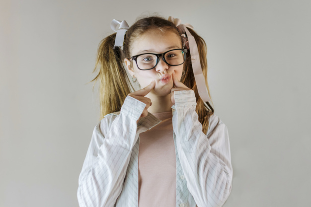 background,ribbon,people,girl,beauty,face,cute,kid,shirt,child,human,person,backdrop,grey background,kids background,clothing,finger,fun,funny,gray,gray background,grey,studio,cute background,hairstyle,beautiful,portrait,cute girl,eyeglasses,pretty,looking,childhood,spectacles,humor,front,casual,blonde,eyewear,ponytail,innocent,silly,touching,cheek,wearing,adorable,closeup,indoors,cheeks,waistup