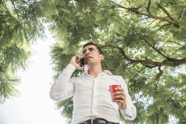 doing,outdoors,connectivity,calling,phone call,sunny,guy,device,call,park,businessman,smartphone,nature,man,phone,technology,tree,business