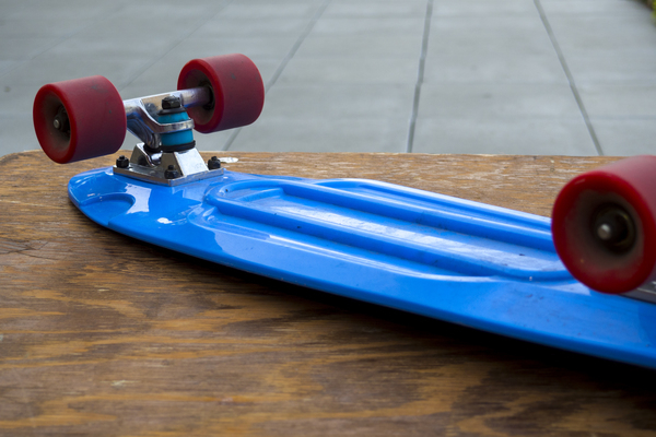 wooden table,wheels,vehicle,sport,skateboard,red,recreation,plastic,outdoors,leisure,fun,equipment,daylight,color,close-up,board,blue
