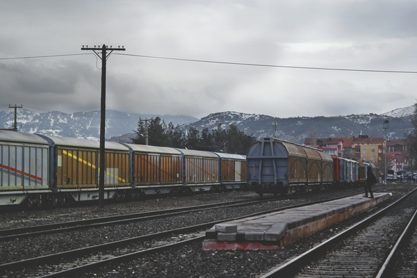 wagon,vehicle,travel,transportation system,train,track,shipment,railway,platform,mountains,gray sky,freight,engine,commerce,clouds,city,carriage,cargo