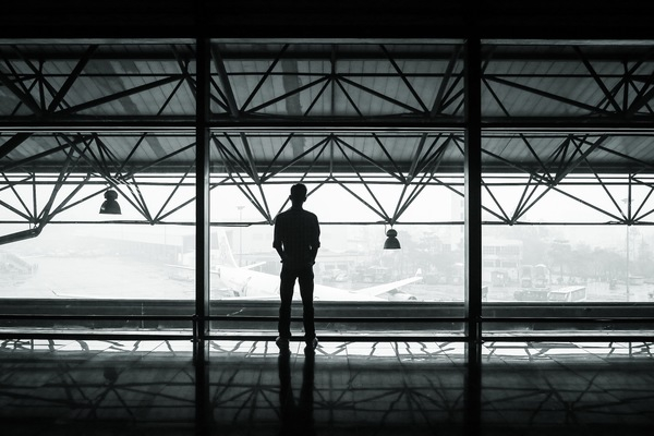 airport,airplanes,hanger,terminal,window,beams,lights,man,shadow,black and white