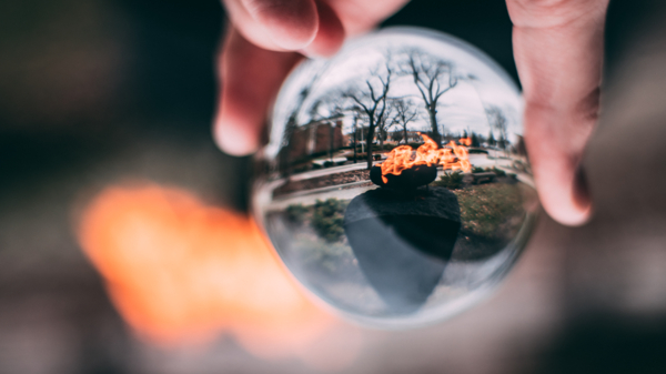 ball-shaped,blur,crystal ball,dark,daytime,fire,flame,glass,hand,holding,outdoors,person,reflections,trees