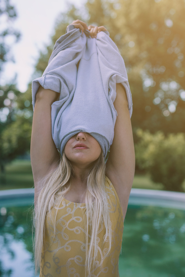 Free: Blonde young woman removing t-shirt over head at outdoors 