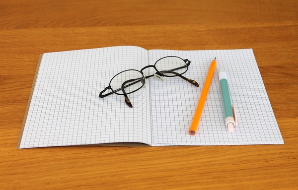 wooden table,wooden surface,retractable pen,pencil,paper,page,notebook,note,graphing paper,glasses,eyewear,eyeglasses,close-up,blank,ballpen