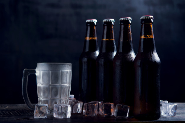 Cold beer with foam in a mug, on a wooden table and a dark background with