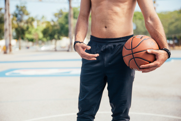 20-25 year old,adult,athlete,athletic,black shorts,fit,game,holding,orange,player,standing,young,background,ball,basketball,braided bracelets,court,fitness,hands,health,healthy,leisure,lifestyle,male,man,masculine,muscular,one,palm,pants,pensive,person,play,pocket,shirtless,single,sportsman,streetball,strong