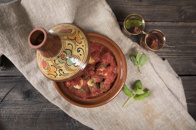 tajine,cooked,prepared,overhead,lay,stew,eastern,homemade,culinary,moroccan,pottery,horizontal,ceramic,cuisine,delicious,flat lay,sauce,beverage,gourmet,top view,mint,top,meal,view,canvas,beef,wooden background,fresh,dish,hot,cloth,traditional,lunch,tomato,wooden,oriental,africa,dinner,fabric,plate,ball,healthy,meat,cup,drink,glass,flat,glasses,arabic,tea,table,green,food,background