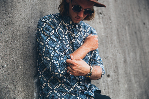 25-30 year old,adult,blue,clothing,grey,hand,hat,one person,portrait,standing,sunglasses,arms,brown hat,caucasian,concrete walls,fashion,fashionable,glass,leans on wall,leather shoes,lifestyle,long hair,male,man,outside,patterned shirt,person,rings,style,stylish,wrist watch