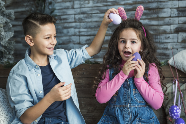 indoors,adorable,siblings,amazed,joyful,bunny ears,seasonal,headband,little,cheerful,small,open mouth,wonder,painted,two,ears,smiling,tradition,playing,horizontal,curly,easter egg,eggs,portrait,sitting,beautiful,festive,wooden background,christian,together,bunny,jeans,wooden,open,symbol,fun,egg,mouth,dress,rabbit,boy,decoration,easter,friends,game,room,child,event,holiday,colorful,kid,happy,celebration,spring,cute,home,girl,background