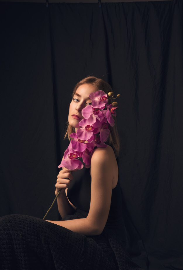 looking at camera,studio shot,pensive,side view,thoughtful,blond,side,casual,bloom,dreaming,looking,calm,pretty,shot,adult,holding,petal,season,bright,sitting,beautiful,view,blossom,fresh,young,dark,female,romantic,branch,studio,lady,model,natural,plant,person,purple,clothes,colorful,black,spring,face,cute,black background,hair,pink,camera,woman,summer,flower,background