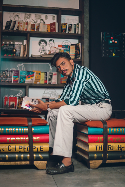 adult,attractive,book stack,books,bookshelves,bookstore,fashion,fashionable,guy,handsome,holding,library,male,man,person,pose,shelf,sit,sitting,wear