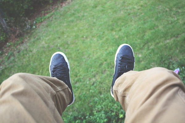 wear,sneakers,shoes,relaxation,person,pants,outside,legs,grass,foot,focus,denim pants,close-up,blur