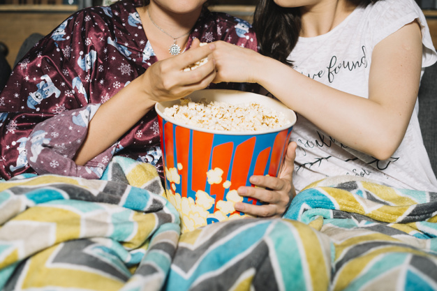 people,hand,woman,home,film,women,movie,modern,life,model,popcorn,friend,relax,female,together,young,snack,entertainment,holding hands,protection,up,lifestyle,weekend,bucket,joy,close,sharing,protect,enjoy,blanket,sit,rest,adult,leisure,relaxation,two,large,hold,girlfriend,casual,domestic,bonding,abundance,closeup,indoors,midsection,waistup
