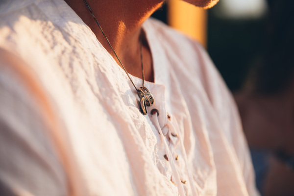 20-25 year old,novelty,ring,sitting,sunlight,accessory,casual,chain,craft,fashion,item,jewel,jewelry,male,man,metal,necklace,outdoor,outside,pendant,platinum,selective focus,shoulders,silver,style,stylish,white shirt