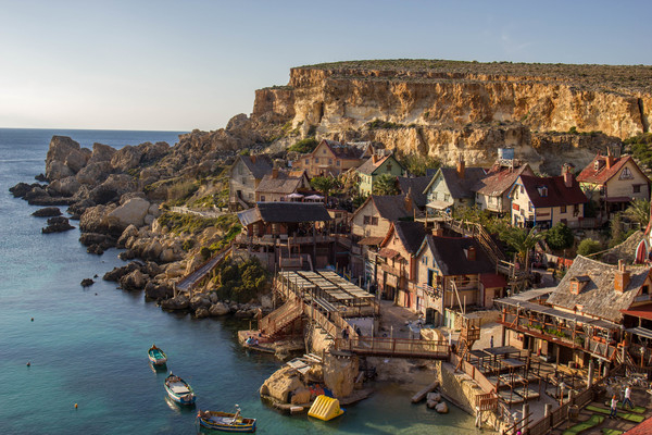 popeye village,mediteranean sea,Malta,Cliffs,rock face,rock,stone,sea,ocean,blue,sky,boats,houses,wood