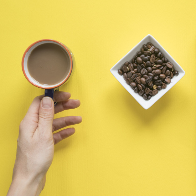 background,coffee,people,hand,yellow,backdrop,person,yellow background,coffee cup,drink,desk,cup,healthy,finger,brown,coffee beans,studio,brown background,simple background,morning