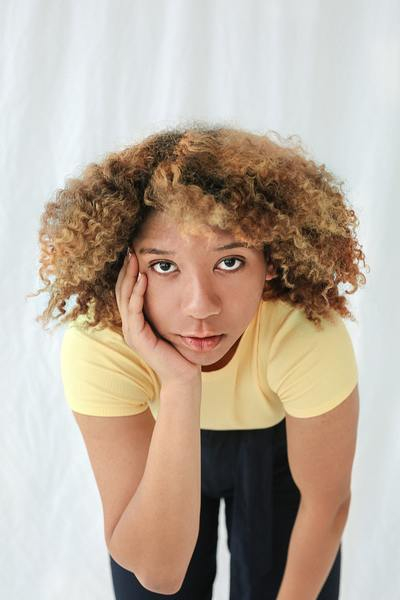 woman,hand,face,thought,think,yellow,t-shirt,curly,hair,black,eyes