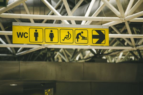 airport,plane,sign,disability,wheelchair,man,yellow,street,building,sign,building,direction,toilet,airport,disability,bathroom,symbol,yellow sign,airport sign,ceiling,access