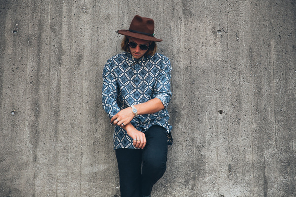 25-30 year old,adult,blue,clothing,grey,hand,hat,one person,portrait,standing,sunglasses,arms,brown hat,caucasian,concrete walls,fashion,fashionable,glass,leans on wall,lifestyle,long hair,male,man,outside,patterned shirt,person,rings,style,stylish,wrist watch