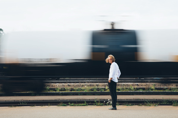 20-25 year old,blur,hand in pocket,platform,railroad,speed,structure,track,young,background,blond,caucasian,city,commuter,departure,dynamic,fast,journey,long haired,look over shoulder,man,motion,rail,railway,selective focus,steel,train,transport,transportation,wrist watch