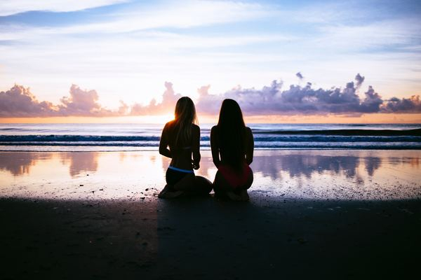 Free: silhouette of two women facing body of water 