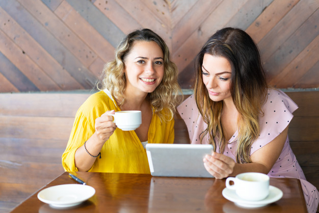 coffee,people,computer,restaurant,camera,table,shop,cafe,coffee cup,tablet,cup,dress,lady,coffee shop,female,young,sitting,drinking,ladies