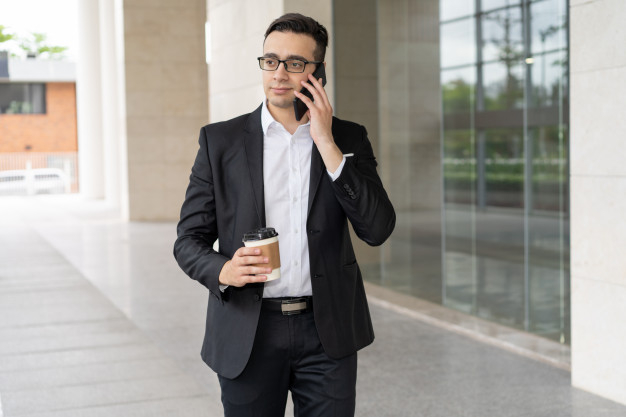 business,building,phone,man,office,mobile,glasses,person,businessman,job,business man,mobile phone,employee,suit,english,walking,outdoor,talking,young,western