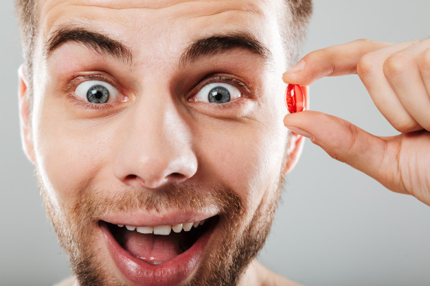 Free: Close up portrait of a happy man holding red capsule Free Photo 