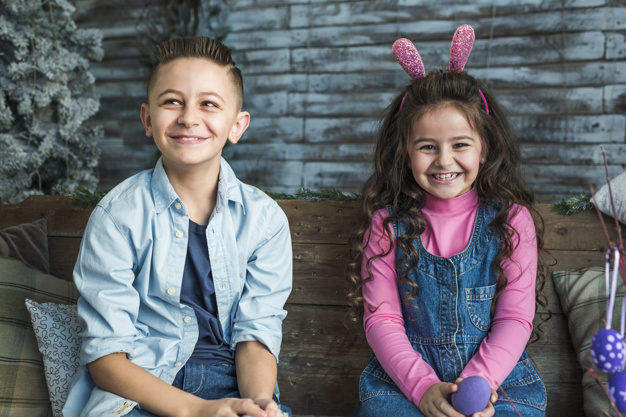 looking at camera,indoors,adorable,siblings,joyful,bunny ears,seasonal,headband,little,cheerful,small,painted,two,ears,looking,smiling,tradition,horizontal,curly,easter egg,eggs,portrait,sitting,beautiful,festive,wooden background,christian,together,bunny,jeans,wooden,symbol,fun,egg,dress,rabbit,boy,decoration,easter,friends,room,child,event,holiday,colorful,kid,happy,celebration,spring,cute,home,girl,camera,background