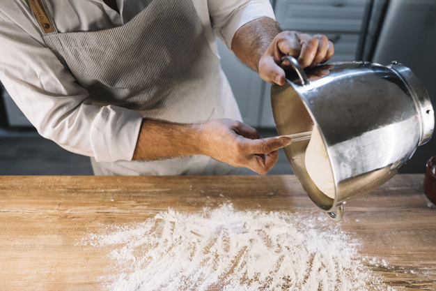 people,man,bakery,kitchen,table,chef,metal,human,board,person,bread,cook,wheat,cooking,spoon,working,wooden,wood table,bowl,steel