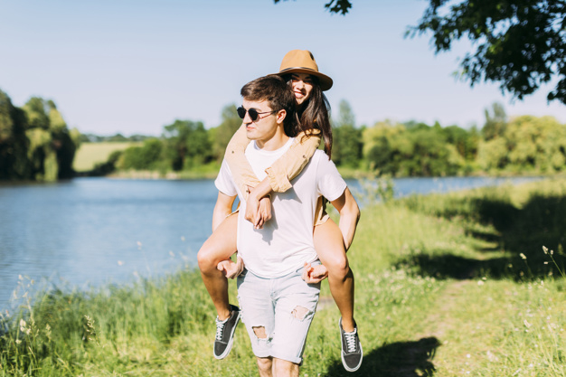people,water,man,nature,grass,couple,person,hat,clothing,sunglasses,tourism,vacation,walking,womens day,female,together,young,lake,back,view