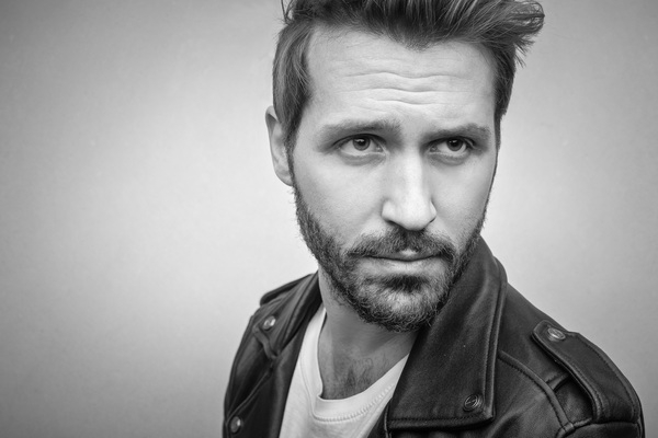 30-35 years old,adult,black,jacket,beard,black-and-white,close-up,eyes,facial expression,fashion,leather,male,man,model,modelling,person,photoshoot,studio wall,white tshirt