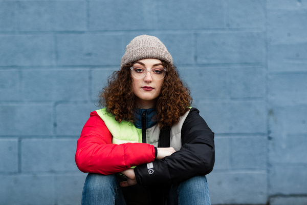 adult,blue background,bright colours,casual,curls,curly,fashion,jacket,outdoors,sitting,wear,woman,Free Stock Photo