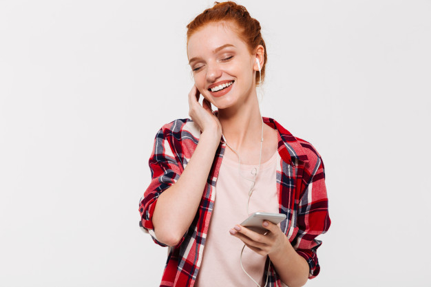 pleased,20s,caucasian,charming,redhead,posing,attractive,inside,casual,single,indoor,smiling,pretty,listening,earphone,adult,alone,closed,ginger,lovely,portrait,beautiful,headphone,young,female,youth,person,smartphone,happy,cute,hands,phone,woman,people,music