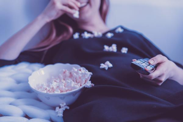 woman,eating,popcorn,blond,smile,happy,television,tv,remote control,remote,spill,bed