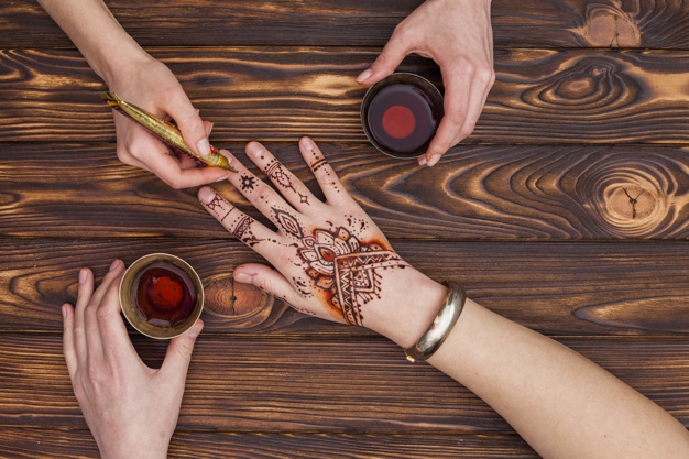 unrecognizable,applying,faceless,body part,making,dye,womans,small,surface,part,mehndi,crop,anonymous,horizontal,master,holding,drinking,beverage,ornate,top view,top,beauty woman,hand painted,holding hands,beautiful,view,tea cup,asian,henna,artist,tool,wooden background,professional,traditional,wood table,culture,skin,brown background,hand drawing,wooden,mug,oriental,brown,pattern background,nature background,natural,ethnic,cup,body,drawing,process,drink,decoration,person,tea,black,tattoo,art,black background,paint,table,woman,ornament,hand,pattern,background